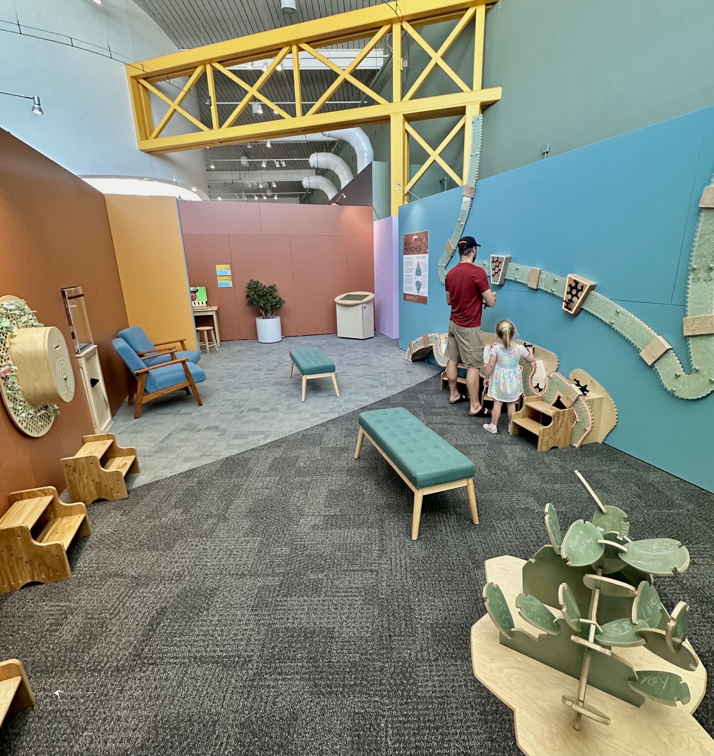 A parent and child are interacting with the "Your Brain on Kindness" exhibit at Explora.